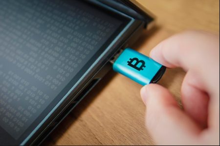 Hardwarowy portfel dla kryptowaluty podłączony do laptopa w ręku człowieka zimny sposób przechowywania kryptowalut na przenośnym nośniku jest sposobem ochrony oszczędności Bezpieczny offline portfel Bitcoin na dysku flash